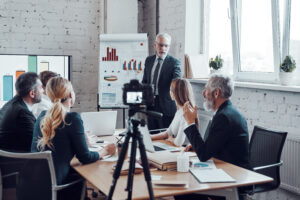 a group of people in a meeting and one person is explaining with a graphs and charts shown