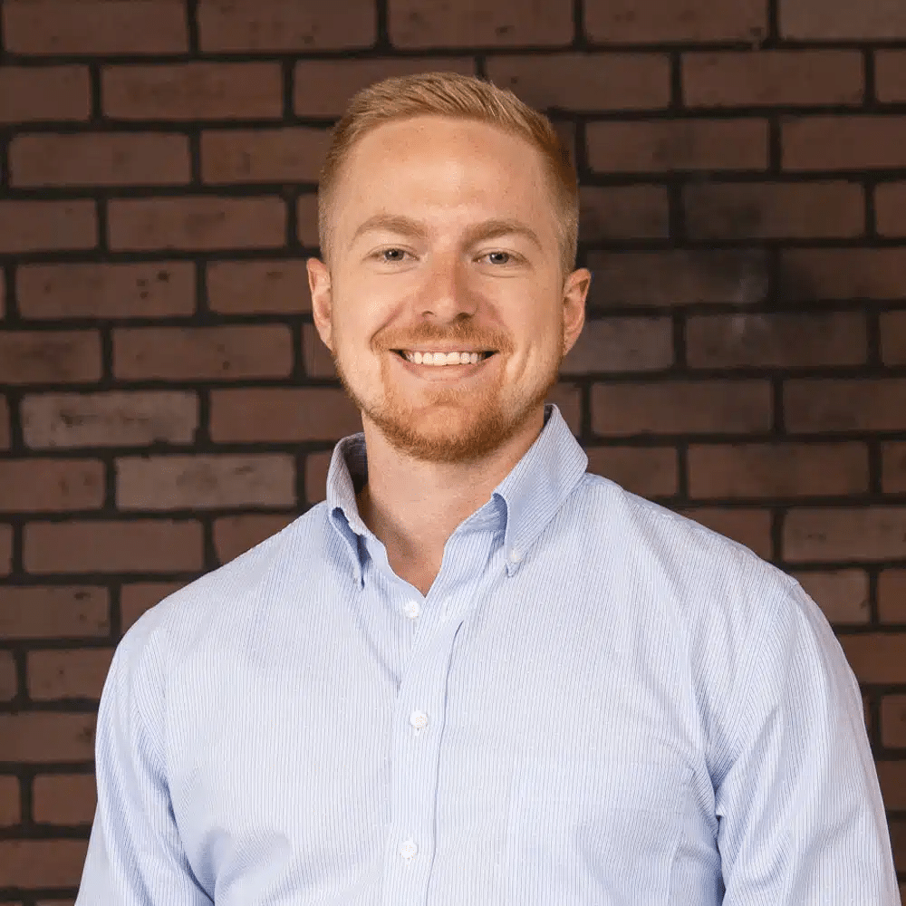 A portrait of our Technical and Automations Specialist, Alden, wearing a blue button up shirt.